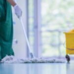 Balde amarelo de limpeza ao lado de profissional em sanitização hospitalar.
