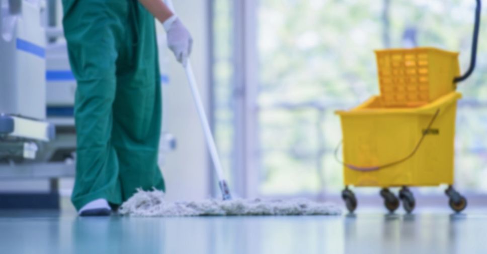 Balde amarelo de limpeza ao lado de profissional em sanitização hospitalar.